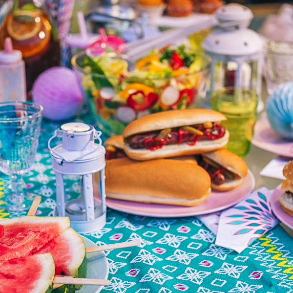 Backyard barbecue spread of burgers, hot dogs, watermelon, and salad on a table