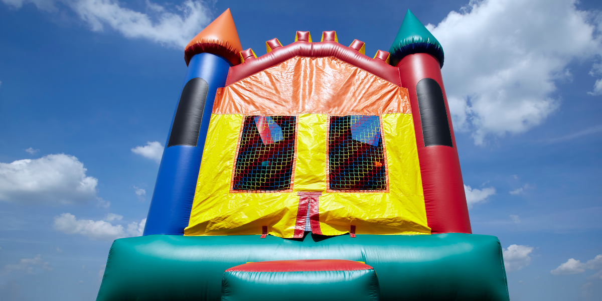 Colorful castle-style inflatable bounce house with turrets set against a blue sky