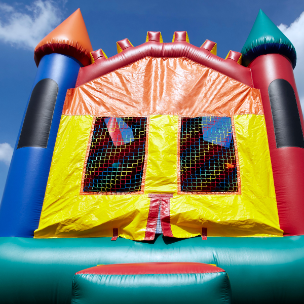 Colorful castle-style inflatable bounce house with turrets set against a blue sky