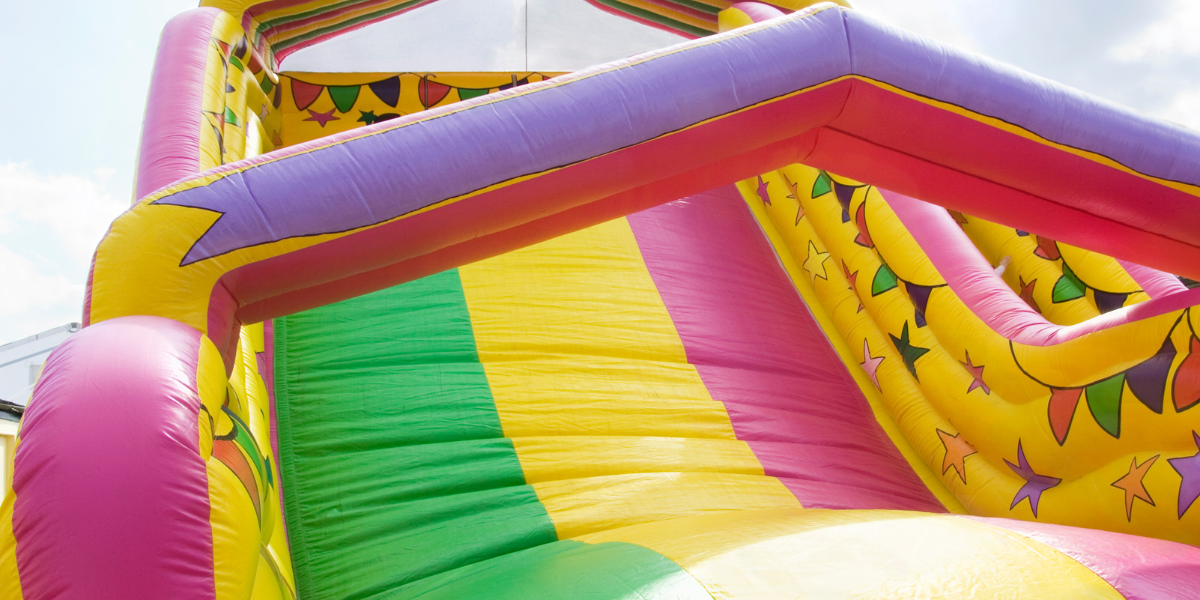 Close-up of a colorful striped inflatable slide showing its vinyl panels and seams
