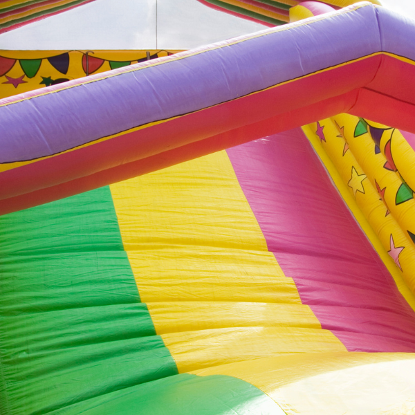 Close-up of a colorful striped inflatable slide showing its vinyl panels and seams