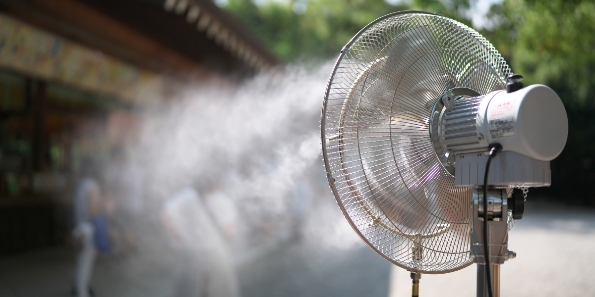 Outdoor misting fan spraying a fine water spray to cool people on a hot day