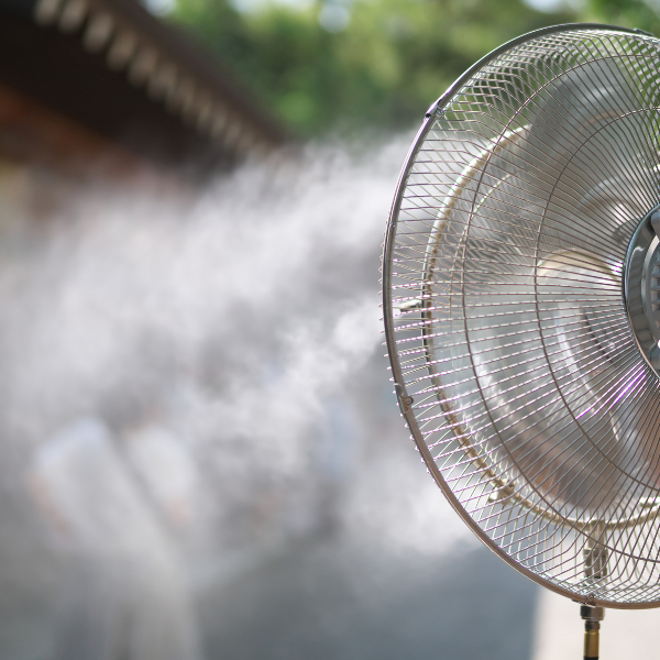Outdoor misting fan spraying a fine water spray to cool people on a hot day