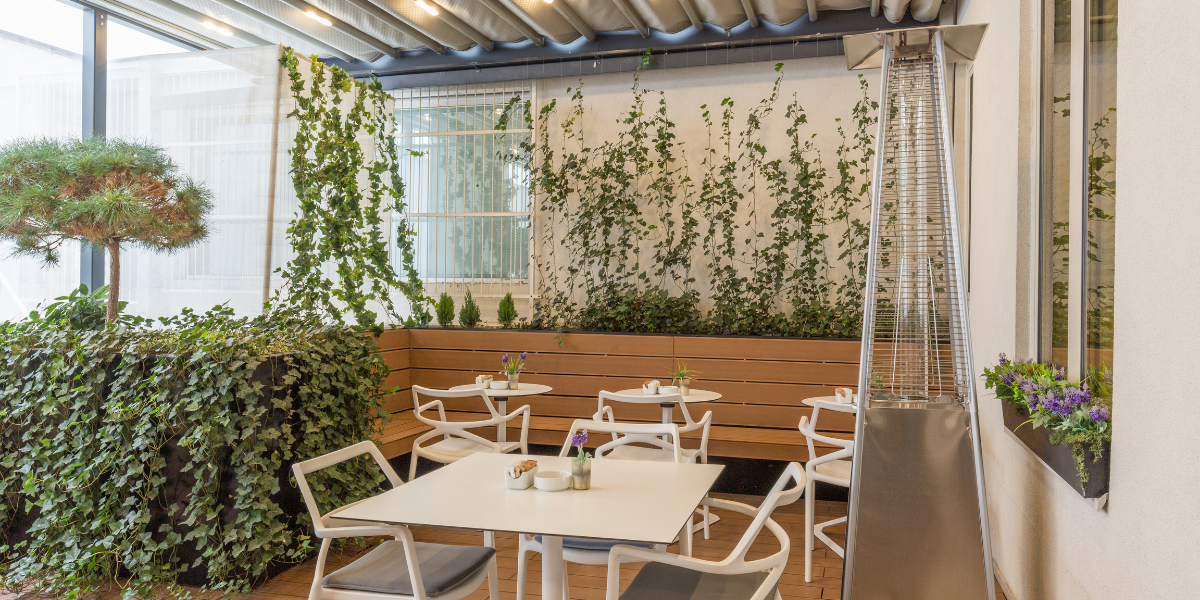 Tall pyramid-style patio heater warming an outdoor dining patio with white furniture