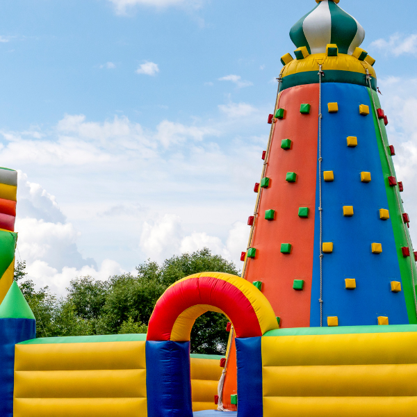 Colorful inflatable play structure with a tall rock-climbing tower and striped slide