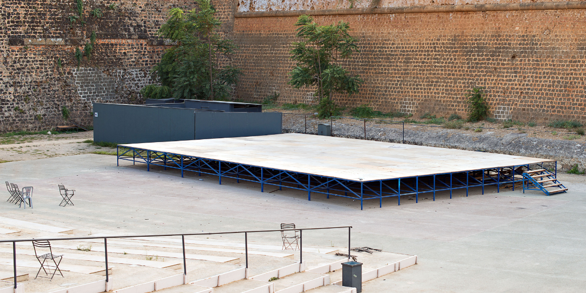Empty raised portable stage platform with a blue steel frame against a brick wall