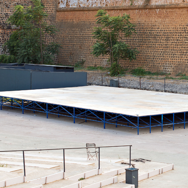 Empty raised portable stage platform with a blue steel frame against a brick wall