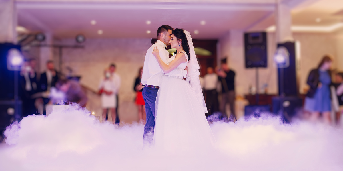 Bride and groom share a first dance on a floor blanketed in low-lying fog machine haze