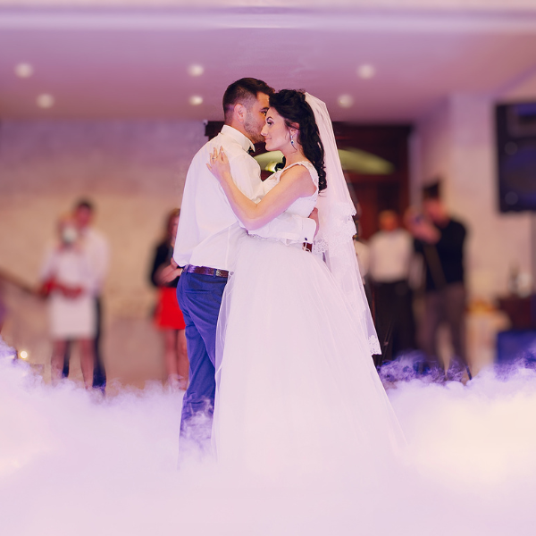 Bride and groom share a first dance on a floor blanketed in low-lying fog machine haze