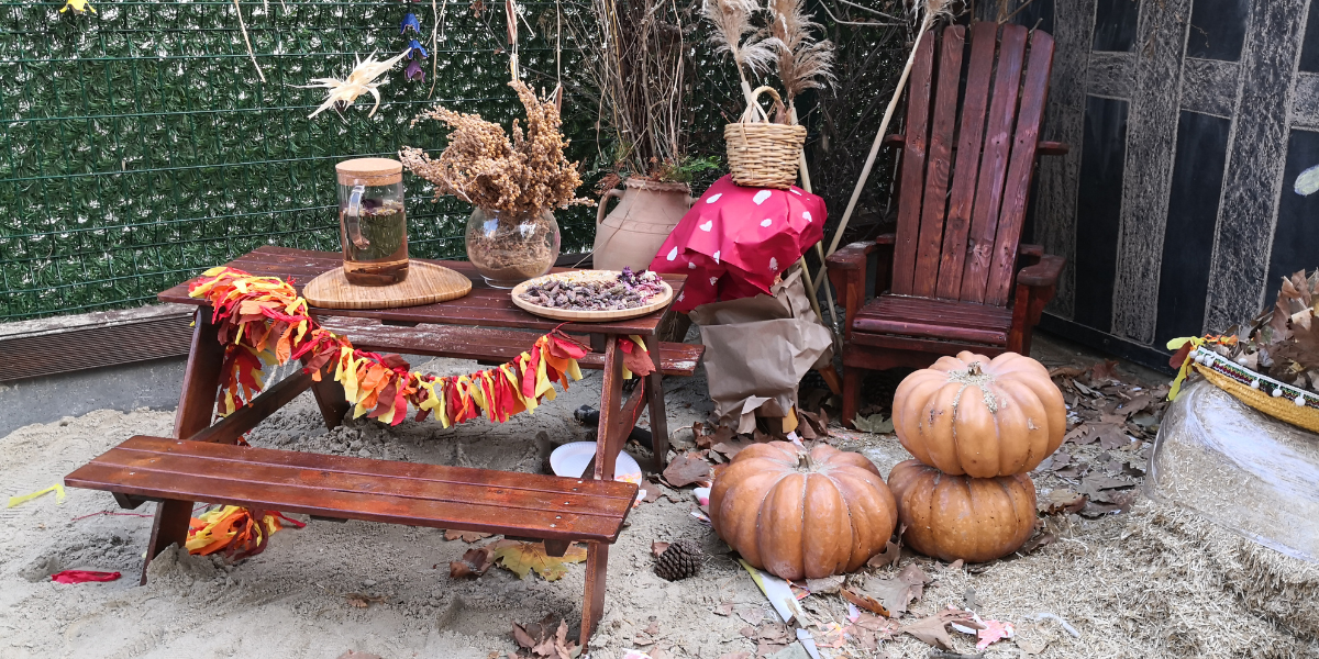 Fall-themed picnic table decorated with pumpkins, autumn leaf garland, and dried florals