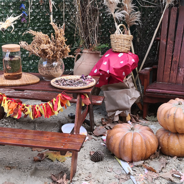 Fall-themed picnic table decorated with pumpkins, autumn leaf garland, and dried florals