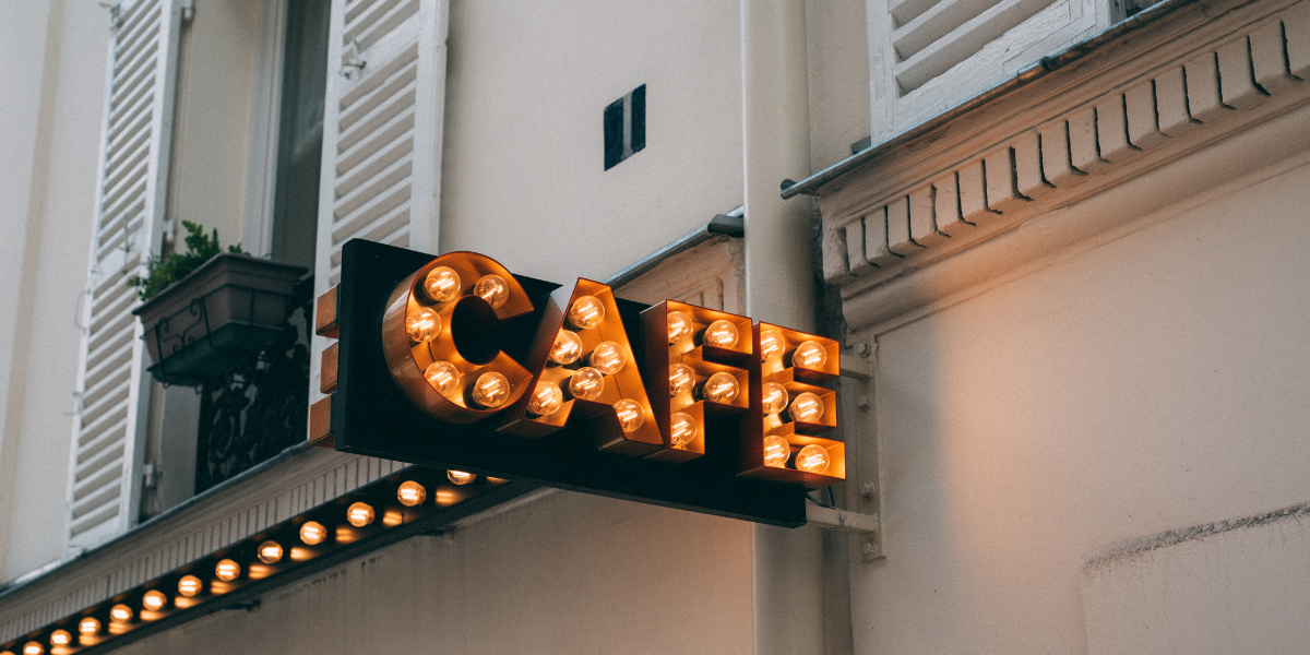 Illuminated marquee-style CAFE sign mounted on a European building facade