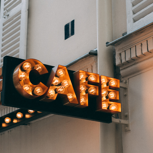 Illuminated marquee-style CAFE sign mounted on a European building facade