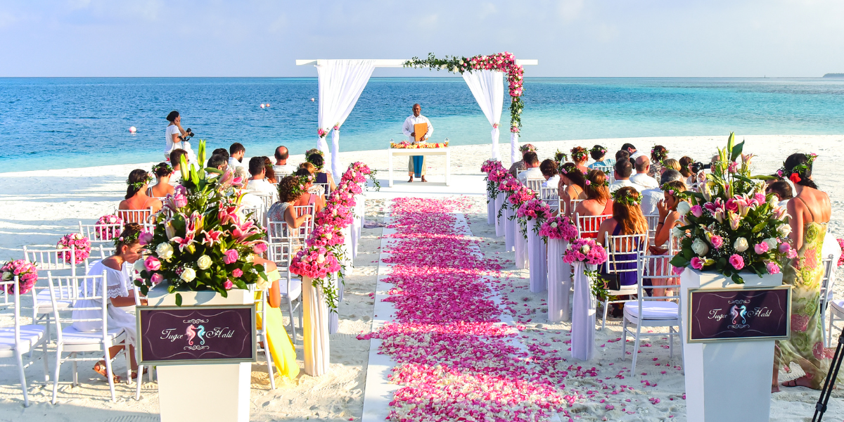 Beach wedding ceremony with a petal-strewn aisle, white chairs, and an ocean backdrop