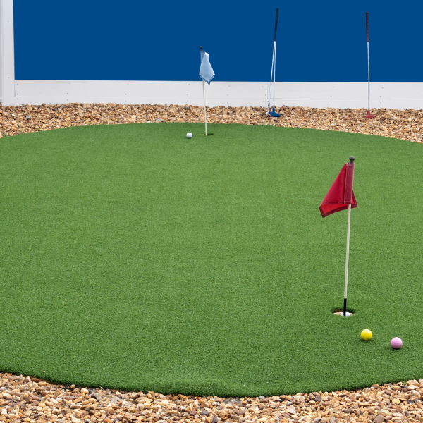 Artificial turf putting green with multiple holes, colored flags, and golf balls