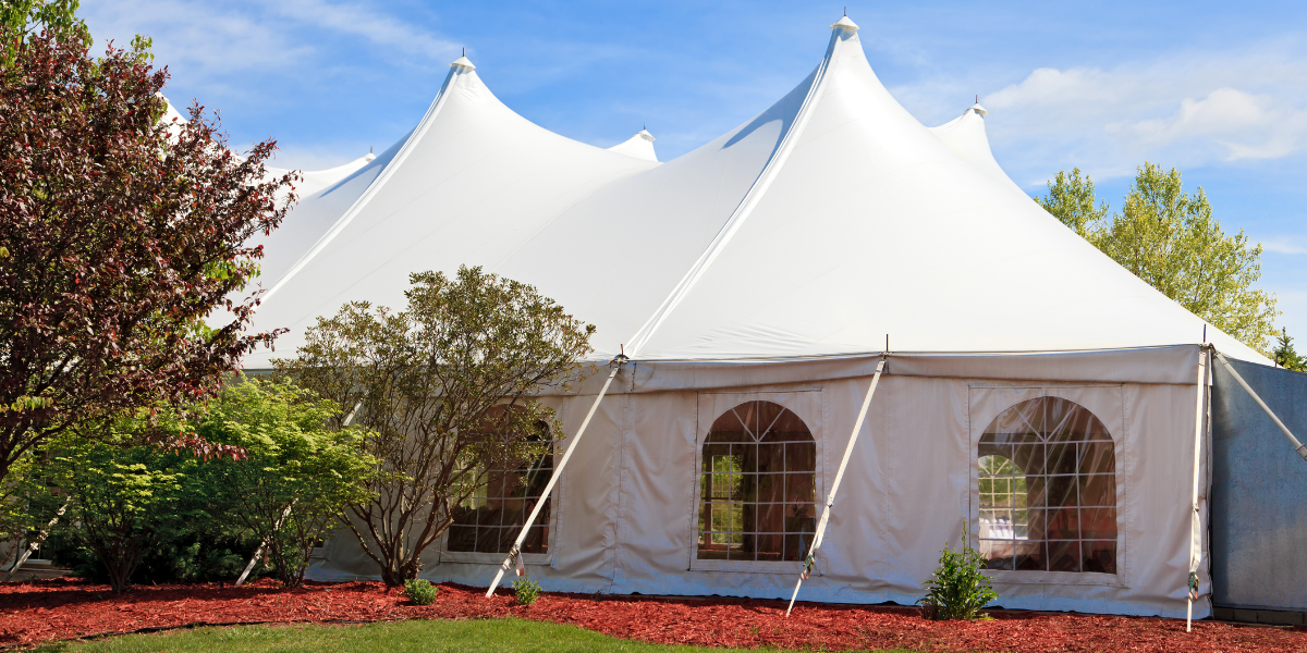 Peaked white pole tent with cathedral-window sidewalls on a landscaped lawn