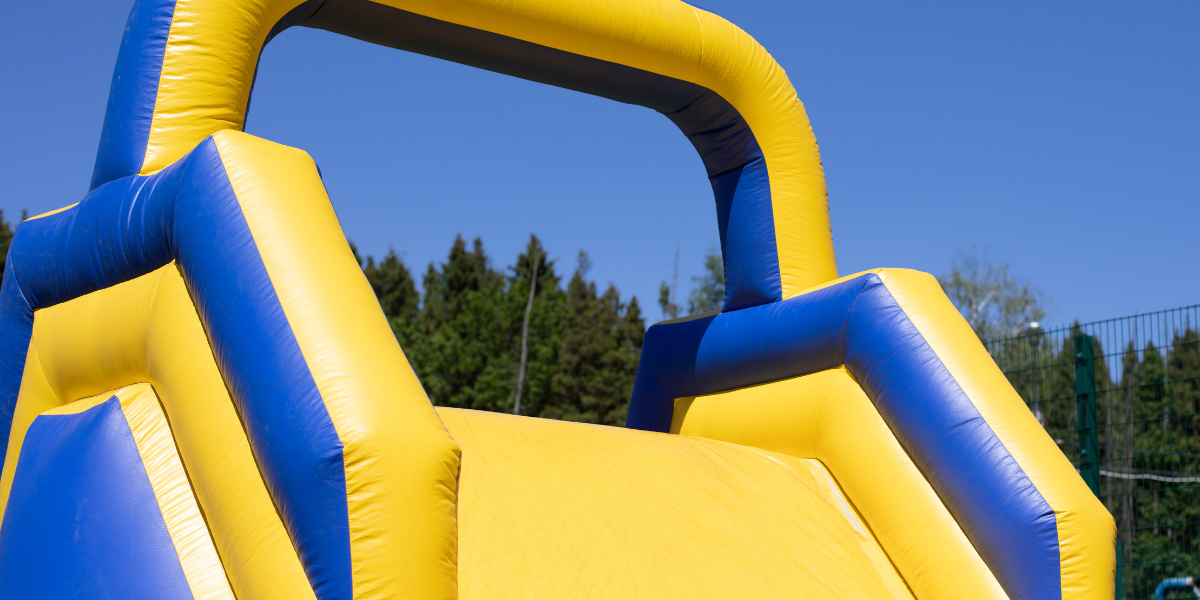 Close-up of a yellow and blue inflatable waterslide against a clear blue sky