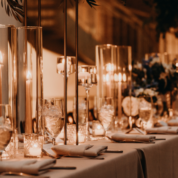 Elegant long table set with gray linens, tall candle cylinders, and floral centerpieces
