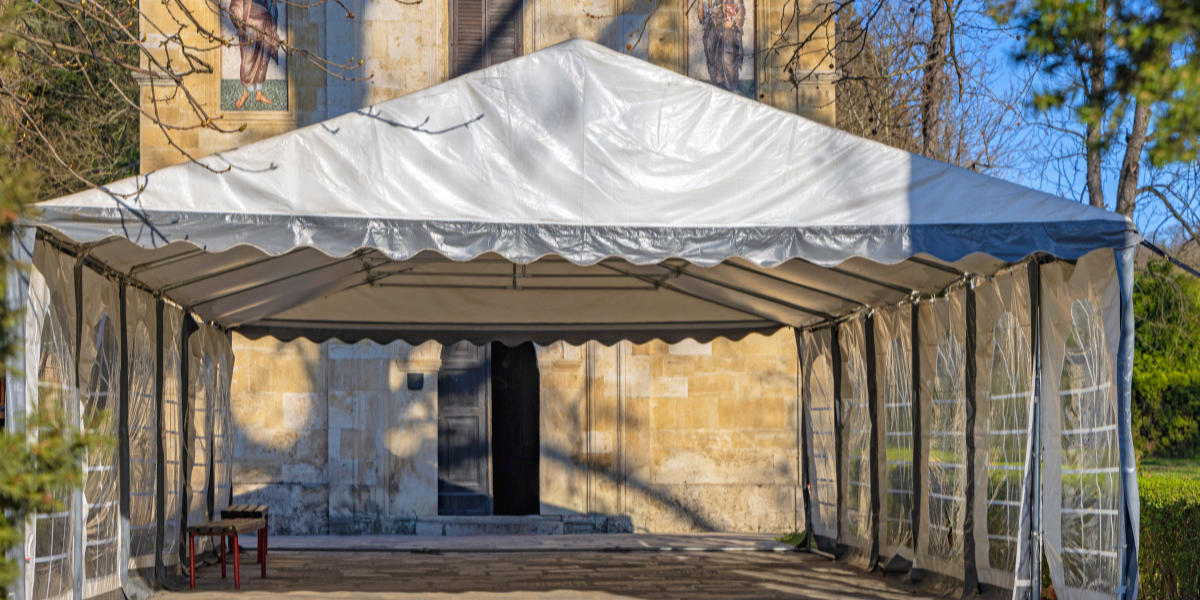 White frame tent set up at the entrance of an old stone church building