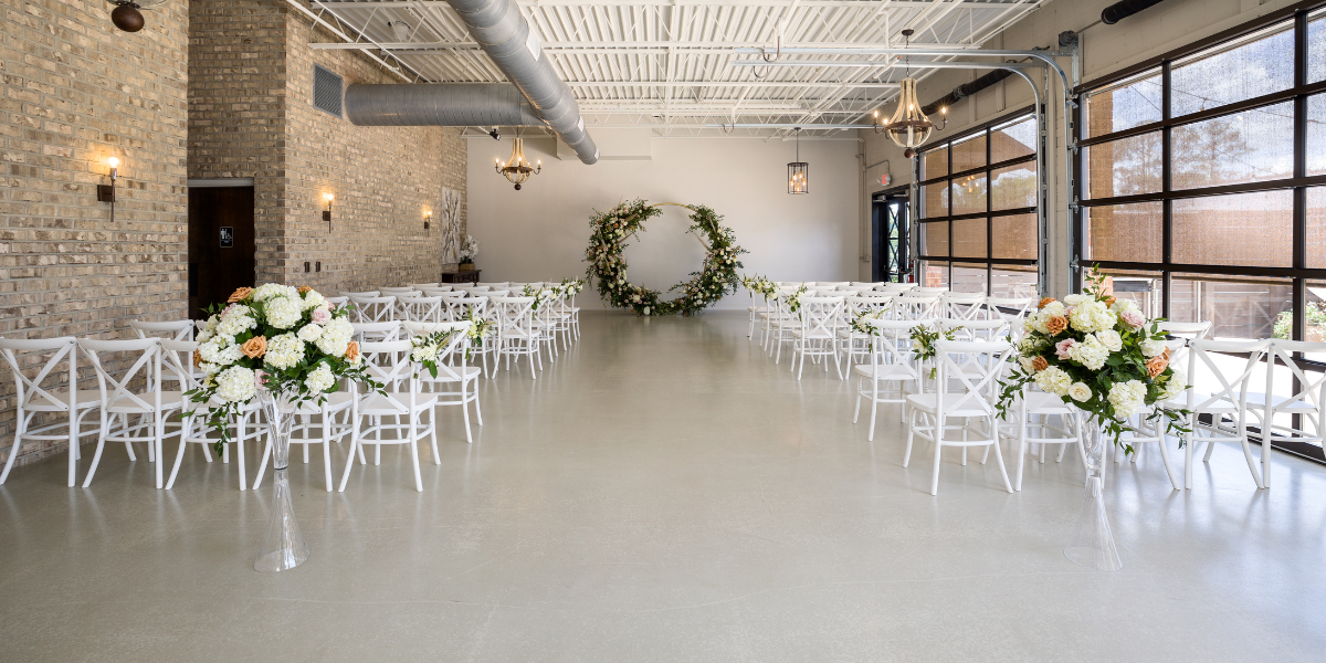 Industrial-style venue with exposed brick set up for a wedding ceremony with white chairs