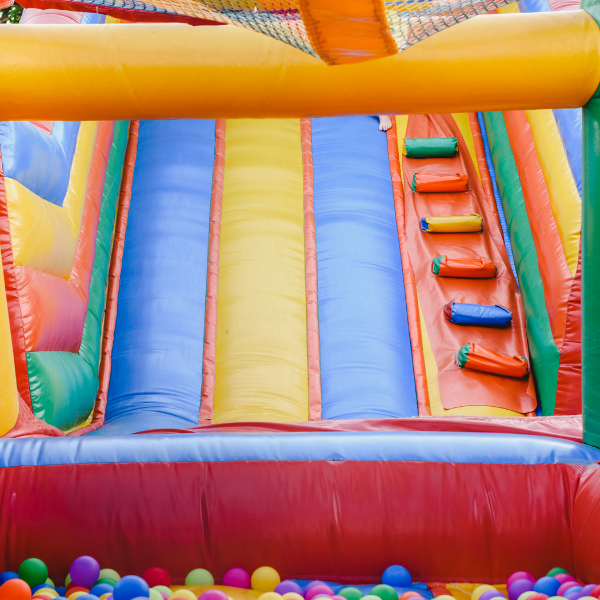 Close-up of a colorful inflatable bounce house slide and ball pit with rainbow balls