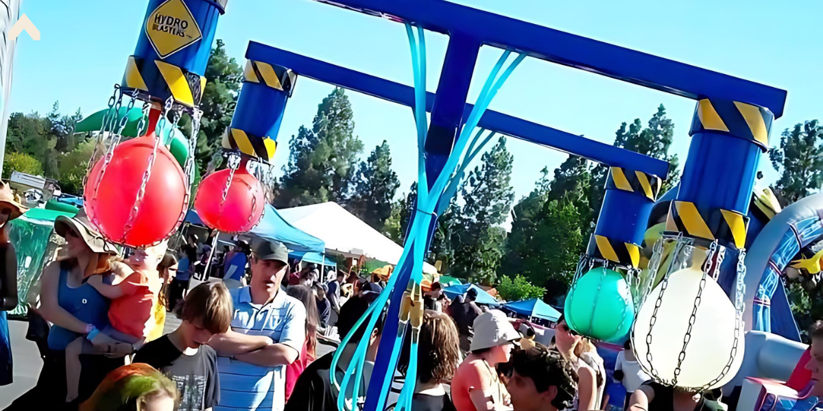 Hydro Blasters carnival game with hanging colored balls on a blue steel frame amid a crowd