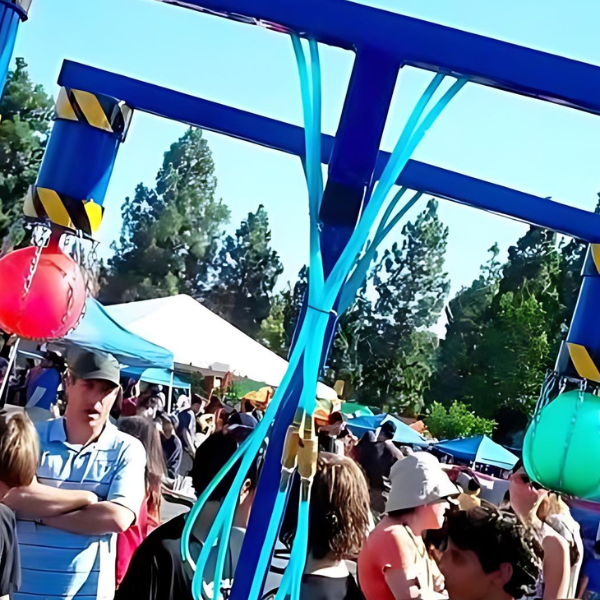 Hydro Blasters carnival game with hanging colored balls on a blue steel frame amid a crowd