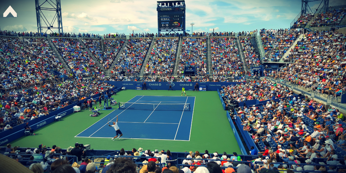 Packed tennis stadium crowd watching two players rally on a blue and green hard court