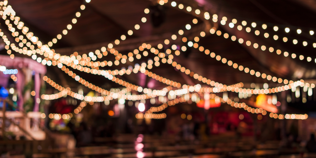 Blurred string lights crisscrossing under a tent roof at a nighttime event