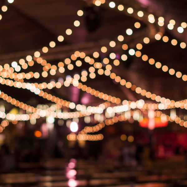 Blurred string lights crisscrossing under a tent roof at a nighttime event