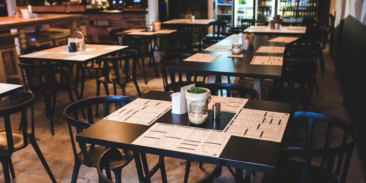 Restaurant interior with black square tables, matching chairs, and menus set for service