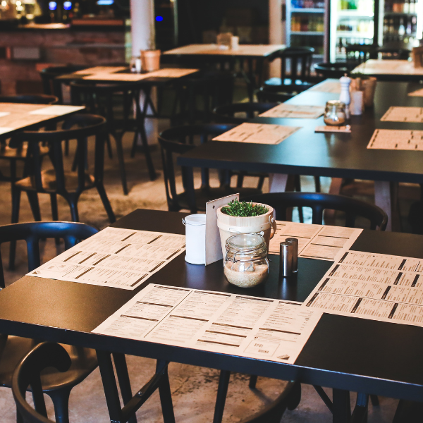 Restaurant interior with black square tables, matching chairs, and menus set for service