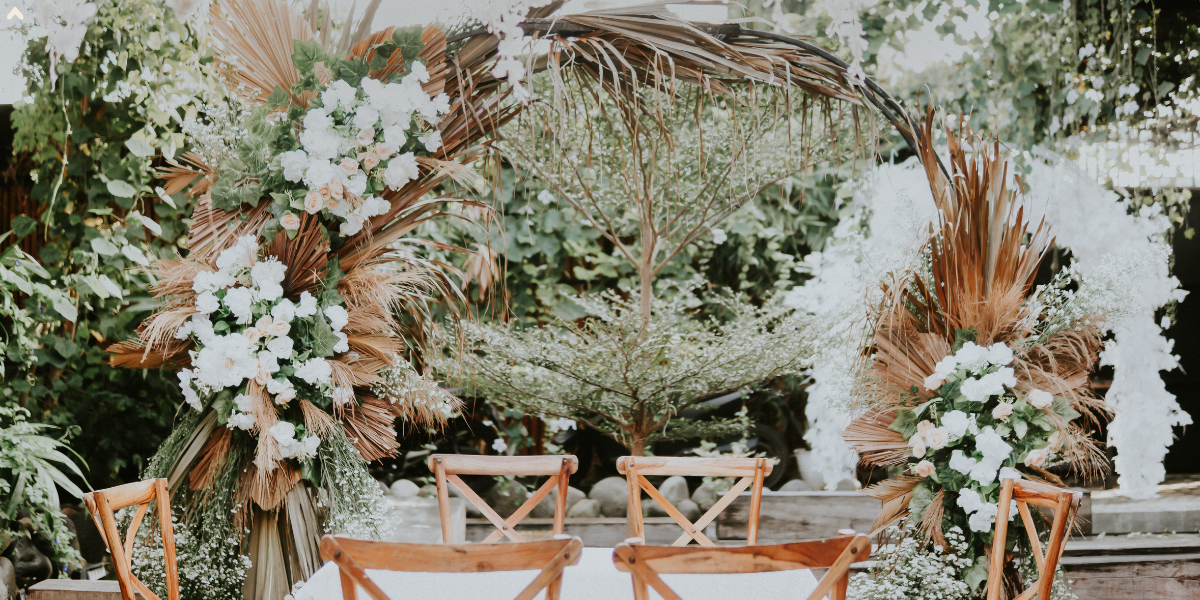 Round floral wedding arch with dried palm fronds and white roses over a sweetheart table