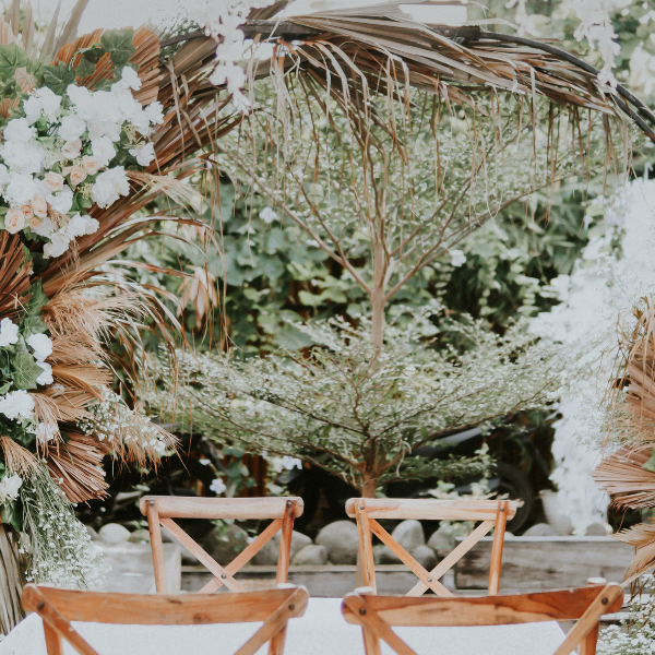 Round floral wedding arch with dried palm fronds and white roses over a sweetheart table