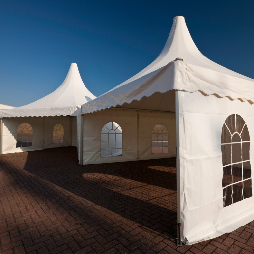 Pagoda-style event tents with cathedral-window sidewalls set on a brick paver patio