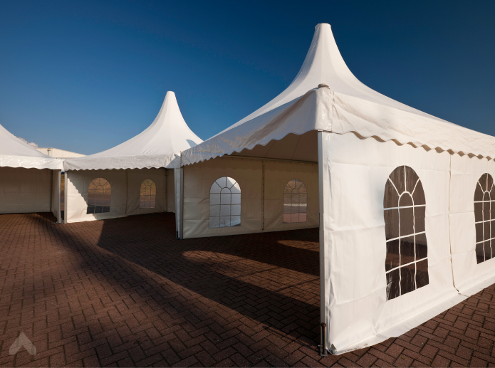Pagoda-style event tents with cathedral-window sidewalls set on a brick paver patio
