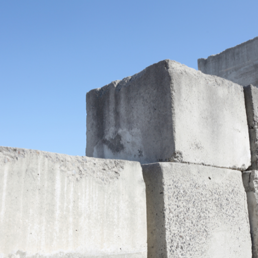 Stacked gray concrete ballast blocks used for tent weighting against a blue sky