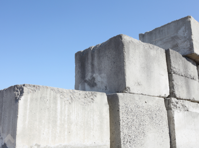 Stacked gray concrete ballast blocks used for tent weighting against a blue sky