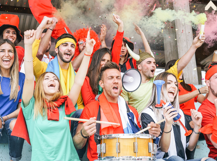 Sports fans cheering in stadium stands with colored smoke flares and a drum