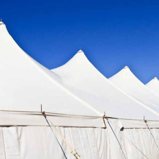 Close-up of white pole tent peaks with guy ropes against a clear blue sky