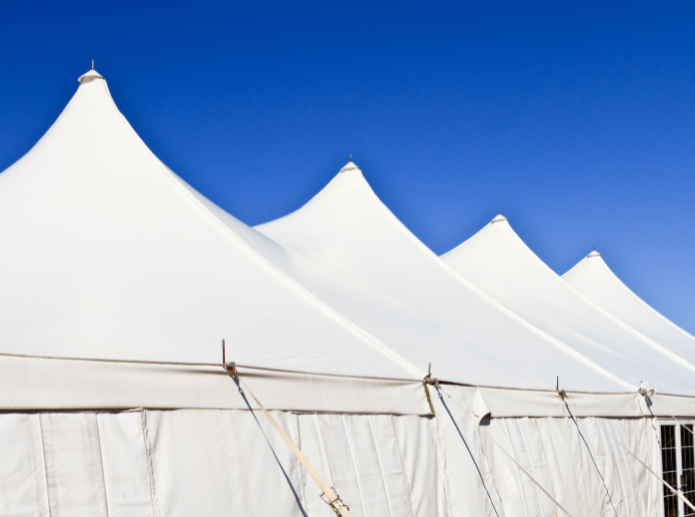 Close-up of white pole tent peaks with guy ropes against a clear blue sky