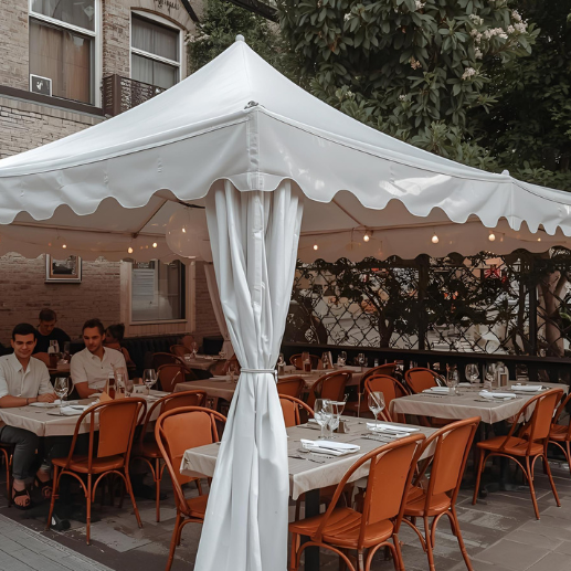 White scalloped-edge canopy covering an outdoor restaurant patio with orange chairs and diners