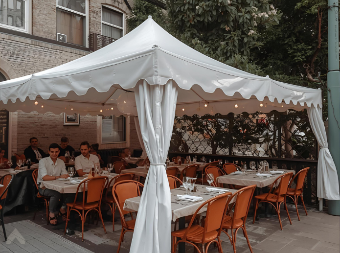 White scalloped-edge canopy covering an outdoor restaurant patio with orange chairs and diners