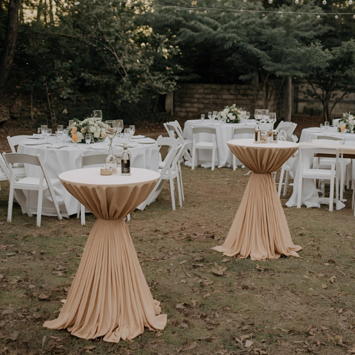 Outdoor reception with round dining tables and tan-draped cocktail tables under string lights