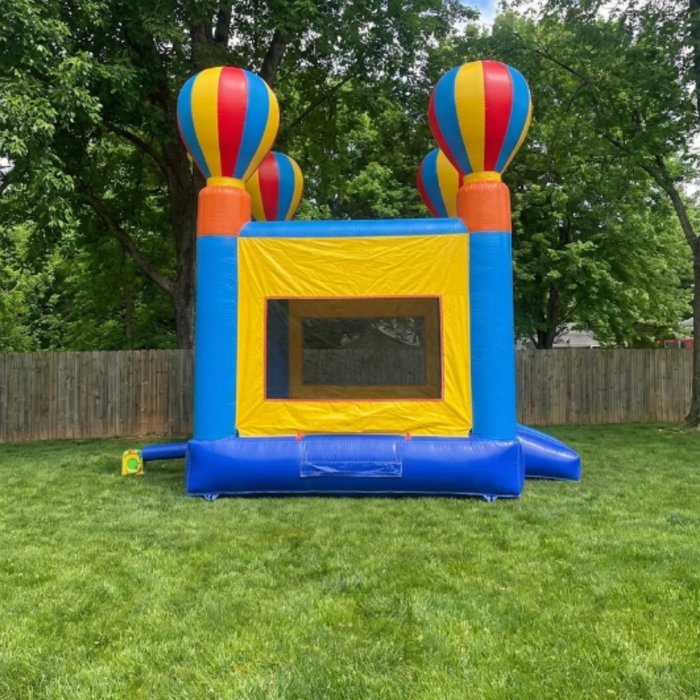 Beyond tent  Commercial-grade 13x13 Celebration Bouncer inflatable on a grass set up with a fence and trees in the back. 