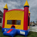 Multicolor inflatable bounce house with red, yellow, and blue colors on a grassy area.