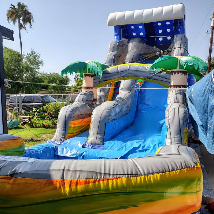 18' Bahama Blast Water Slide with misting hose spraying water, installed in a residential yard with a parked car and palm tree visible