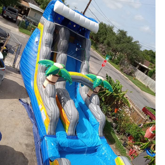 18' Bahama Blast Water Slide installed on a residential street driveway, stop sign and parked truck visible in the background
