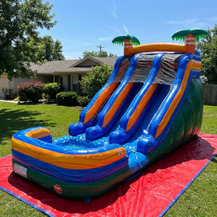 Beyond Tent 18' Double Lane Splash Wet and Dry Slide set up in a residential backyard on a red ground tarp, water flowing down the dual lanes, house and trees in background