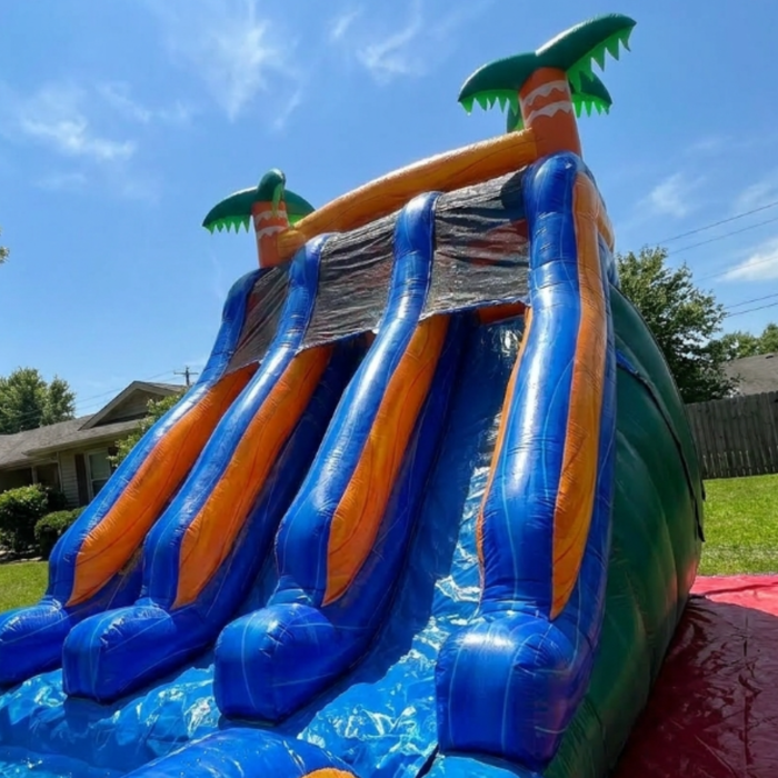 Beyond Tent 18' Double Lane Splash Wet and Dry Slide low angle view of the four wet slide lanes against a blue sky, palm tree toppers and wood privacy fence in background